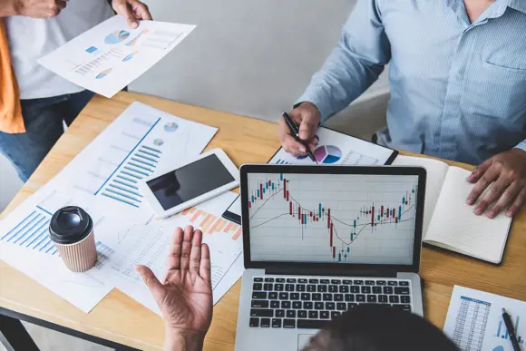 Three people reviewing a financial chart on a computer Three people reviewing a financial chart on a computer