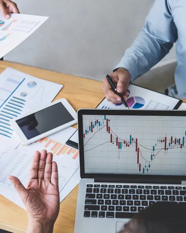 Three people reviewing a financial chart on a computer Three people reviewing a financial chart on a computer