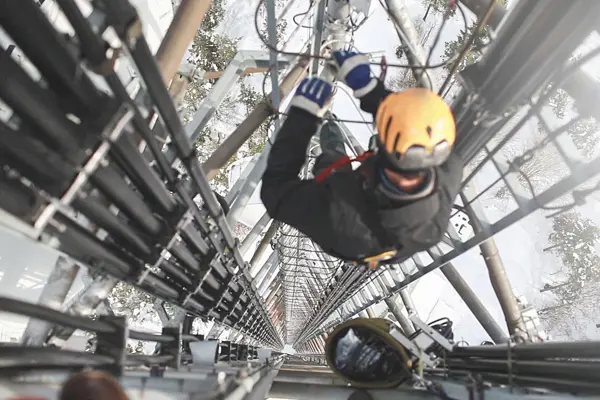 An image of a construction worker climbing the phone tower An image of a construction worker climbing the phone tower