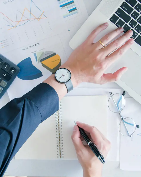 Hand on a desk with a laptop, calculator and documents Hand on a desk with a laptop, calculator and documents