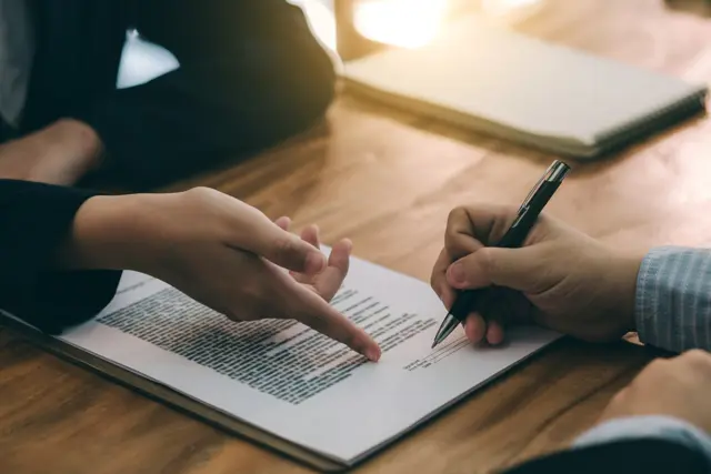 Two hands pointing towards a document Two hands pointing towards a document