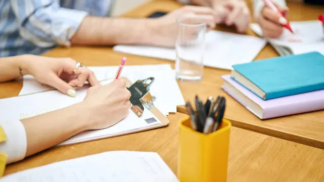 People taking notes at a table People taking notes at a table