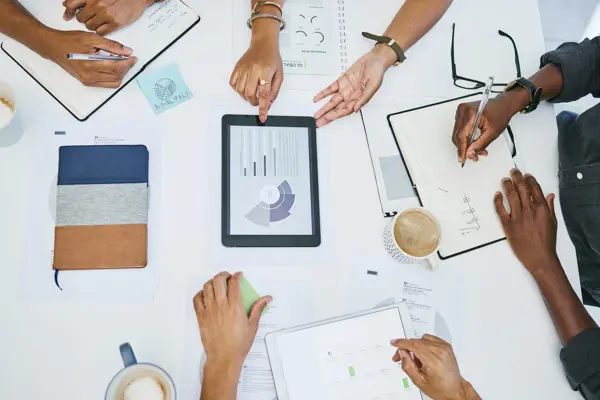 Four people working around a table collaborating on a business value assessment Four people working around a table collaborating on a business value assessment