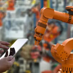 Manufacturing machinery and a person holding a tablet. Manufacturing machinery and a person holding a tablet.