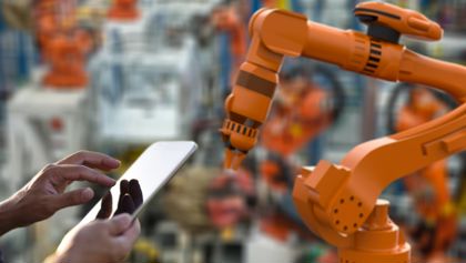 Manufacturing machinery and a person holding a tablet. Manufacturing machinery and a person holding a tablet.