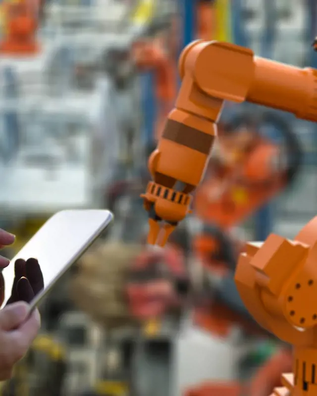 Manufacturing machinery and a person holding a tablet.  Manufacturing machinery and a person holding a tablet.