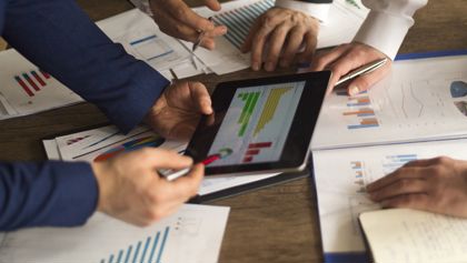 Three people reviewing a financial chart 