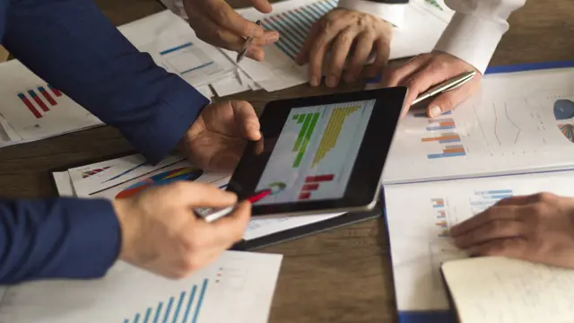 Three people reviewing a financial chart Three people reviewing a financial chart