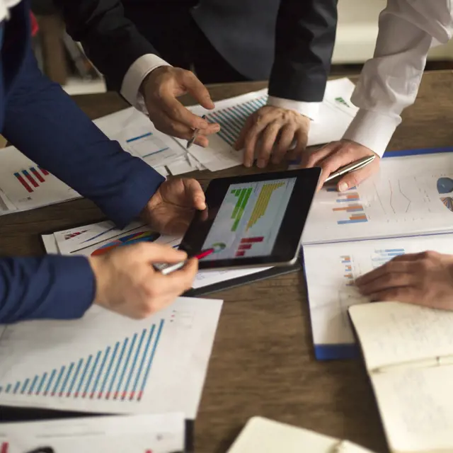 Three people reviewing a financial chart  Three people reviewing a financial chart