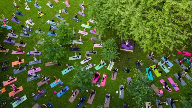 Large group of people doing yoga in a park on colorful yoga mats Large group of people doing yoga in a park on colorful yoga mats